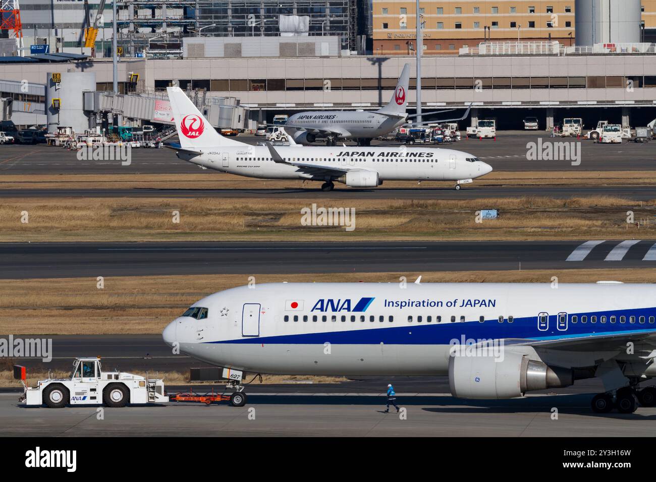 Eine Boeing 767-381(er) mit All Nippon Airways (ANA) wird von einem Schlepper vor einer JAL Boeing 737-846 am Haneda International Airport, Tokio, Japan, gezogen Stockfoto