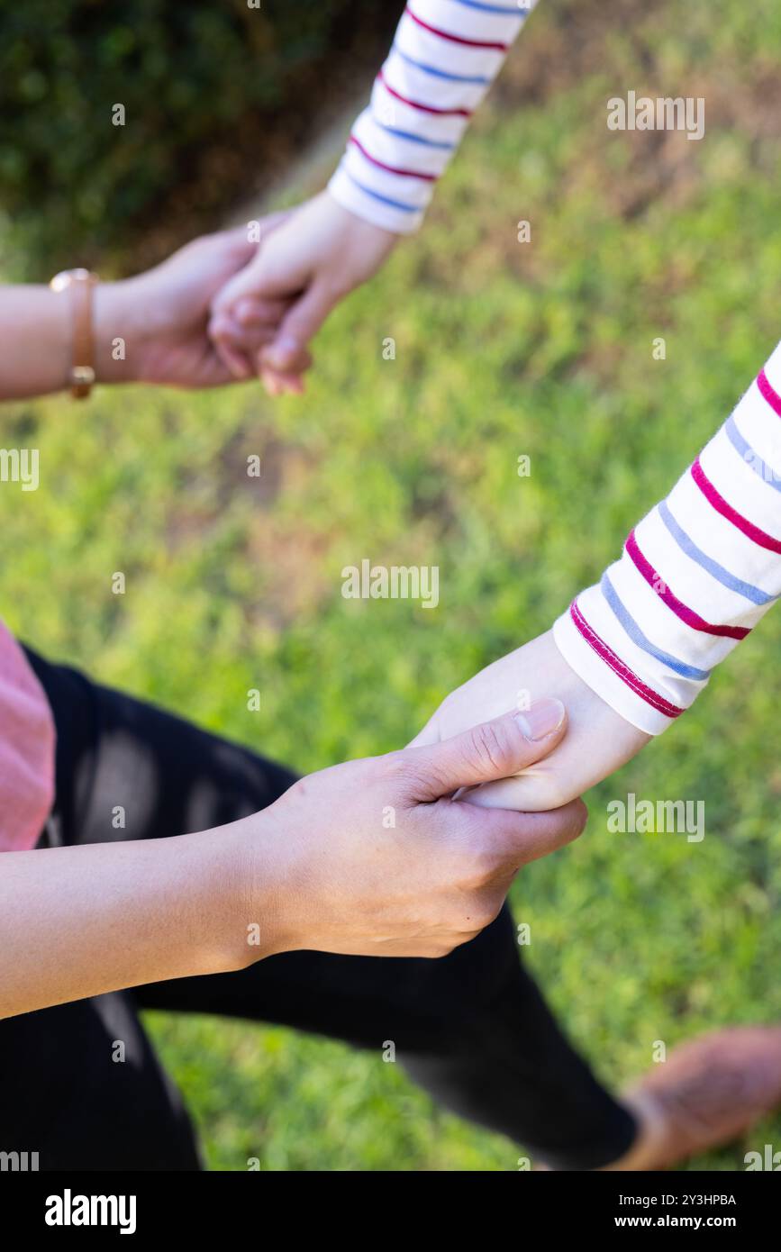Im Garten, Hände haltend, asiatische Mutter und Tochter kleben im Freien in lässiger Kleidung Stockfoto