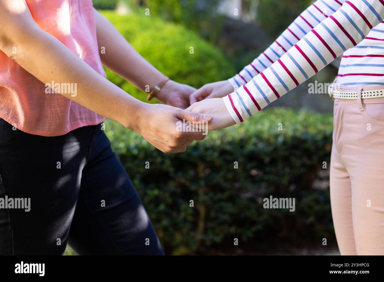 Im Garten, Hände haltend, asiatische Mutter und Tochter, die sich im Freien verbinden und unterstützen Stockfoto