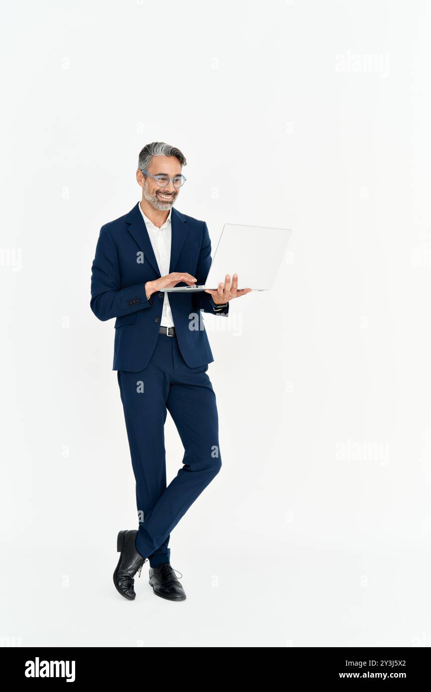 Glücklicher reifer Geschäftsmann, der einen Laptop benutzt, der auf weißem Hintergrund steht. Stockfoto