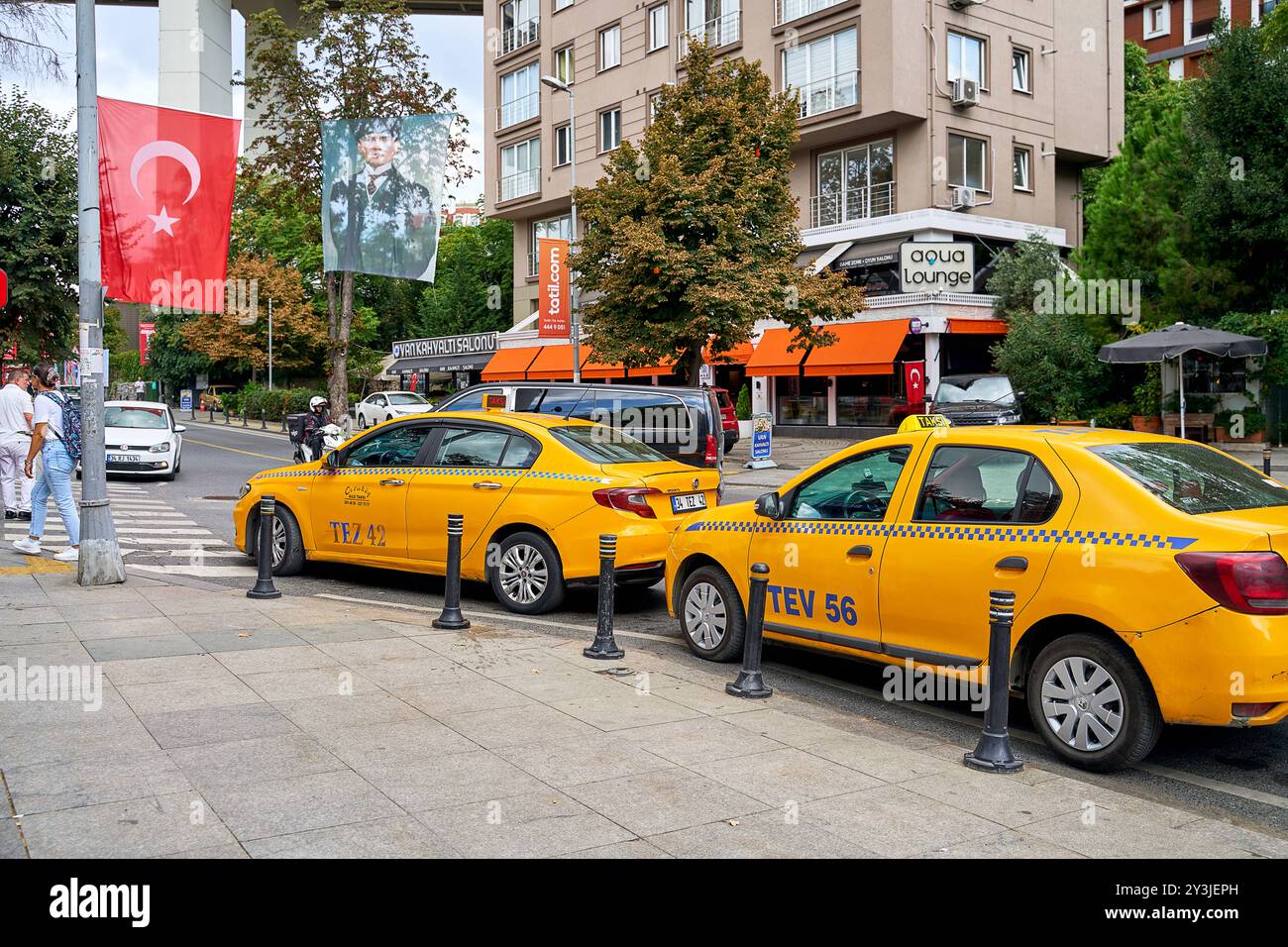 Istanbul, Türkei - 2. September 2024: Gelbe Taxis warten in einer belebten Straße in Istanbul, flankiert von der türkischen Flagge und einem Porträt von Atatürk *** Gelbe Taxis warten in einer belebten Straße in Istanbul, flankiert von der türkischen Flagge und einem Porträt von Atatürk Stockfoto Istanbul, Türkei - 2. September 2024: Gelbe Taxis warten in einer belebten Straße in Istanbul, flankiert von der türkischen Flagge und einem Porträt von Atatürk *** Gelbe Taxis warten in einer belebten Straße in Istanbul, flankiert von der türkischen Flagge und einem Porträt von Atatürk Stockfoto