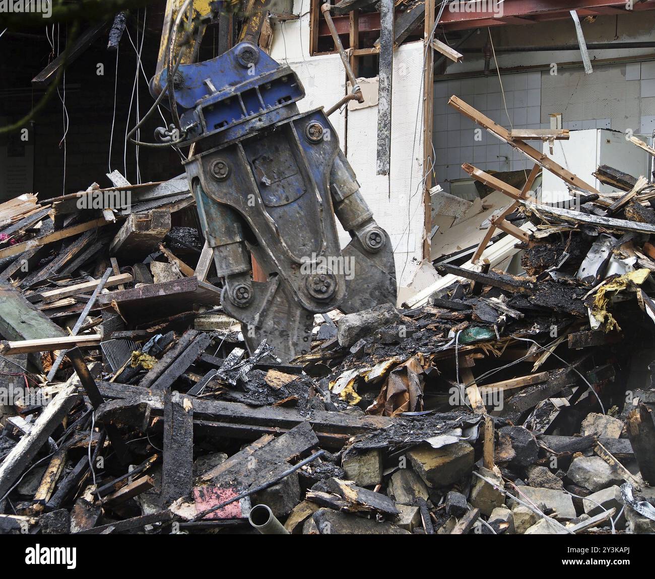 Eine Abbruchschere, die an der Demontage eines zerstörten Hauses arbeitet Stockfoto