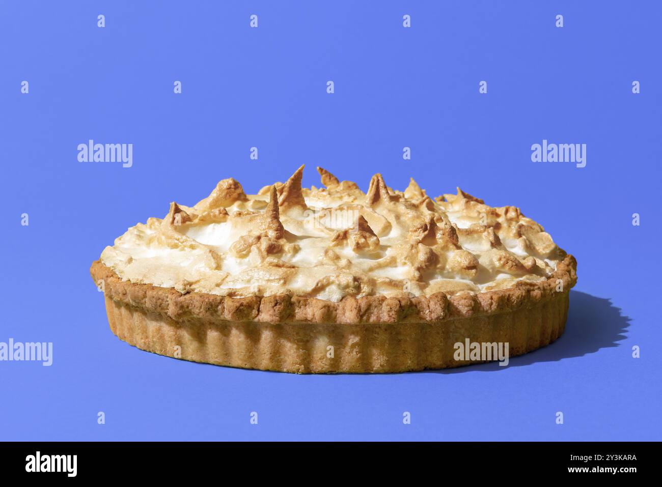 Köstlicher hausgemachter Baiser-Kuchen mit Zitronengeschmack, minimalistisch auf einem blauen Indigo-Tisch. Zitronen-Baiser-Torte isoliert auf einem bunten Bach Stockfoto