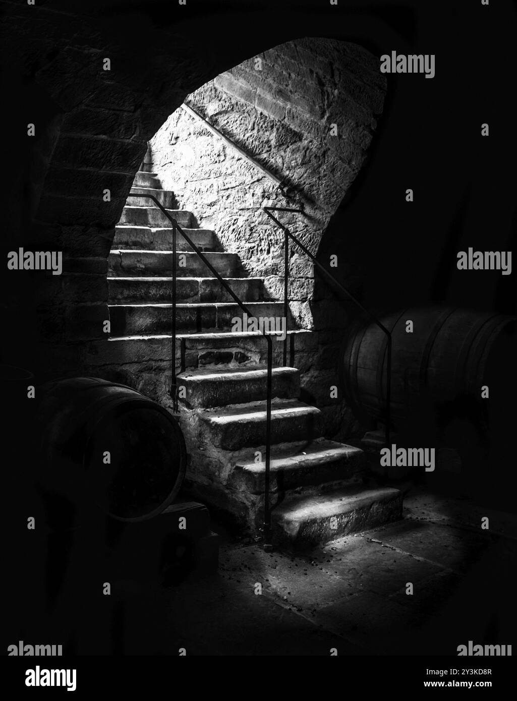 Dramatisches Schwarzweißbild mit alten Steintreppen, die in einen verlassenen Weinkeller führen, mit dunklen Schatten und kleinen Lichtstrahlen Stockfoto