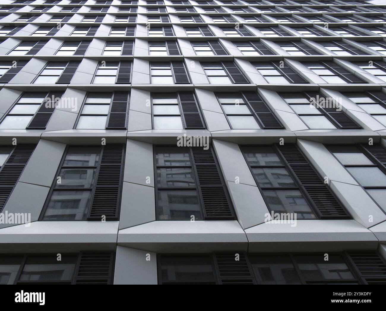 Nahaufnahme eines modernen Hochhausgebäudes mit geometrischer weißer Verkleidung und dunklen Fenstern Stockfoto