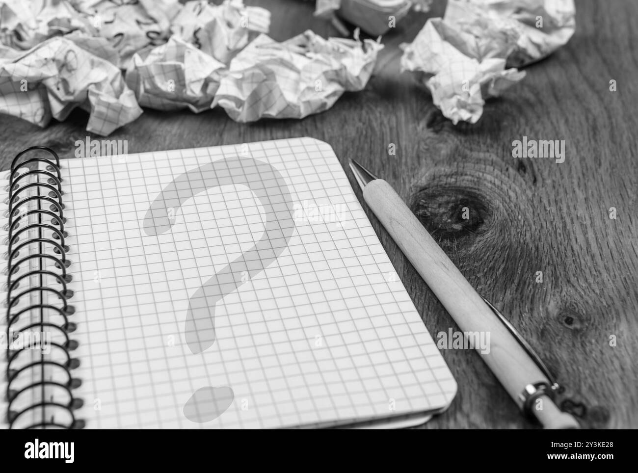 Grafik Notebook mit Question mark auf seiner Seite und geworfenen Entwürfe auf hölzernen Schreibtisch in monochromen Einstellungen Stockfoto