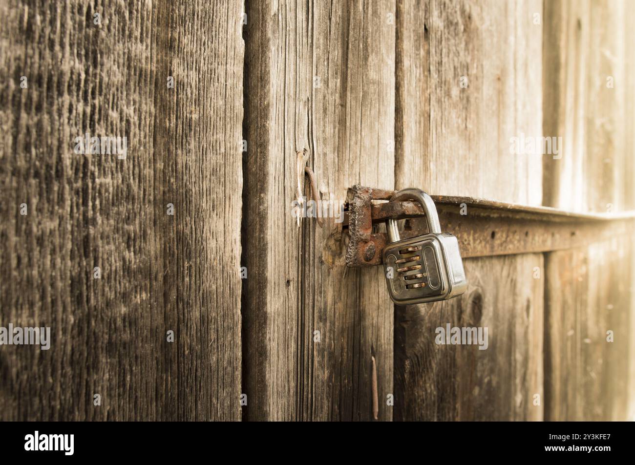 Schließen oben mit einem Metall Schloss an der Tür eines alten hölzernen Scheune Stockfoto