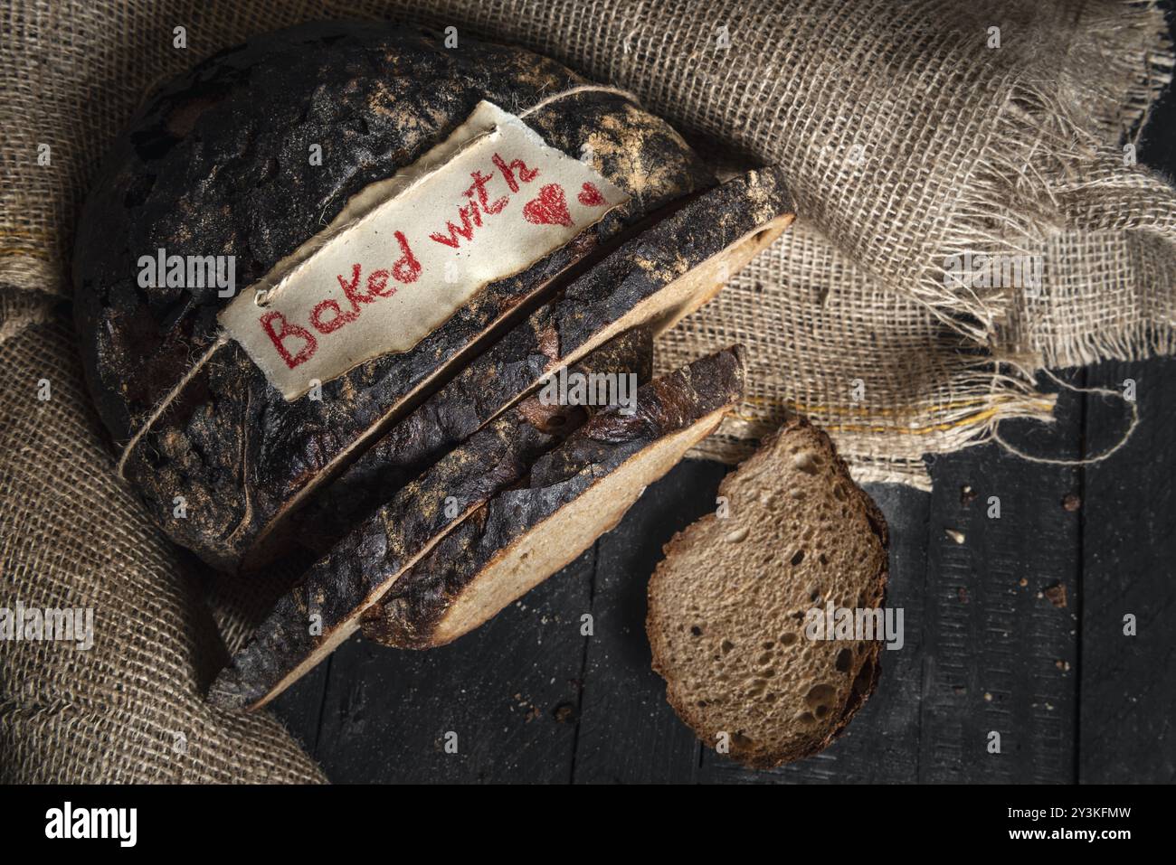 Knuspriges deutsches braunes Brot und gebacken mit Liebesbotschaft auf einem Tag, auf einem Jutesack. Gesundes Roggenbrot. Ober-Ansicht von Diätbrot. Hausgemachtes, einfaches Essen Stockfoto Knuspriges deutsches braunes Brot und gebacken mit Liebesbotschaft auf einem Tag, auf einem Jutesack. Gesundes Roggenbrot. Ober-Ansicht von Diätbrot. Hausgemachtes, einfaches Essen Stockfoto