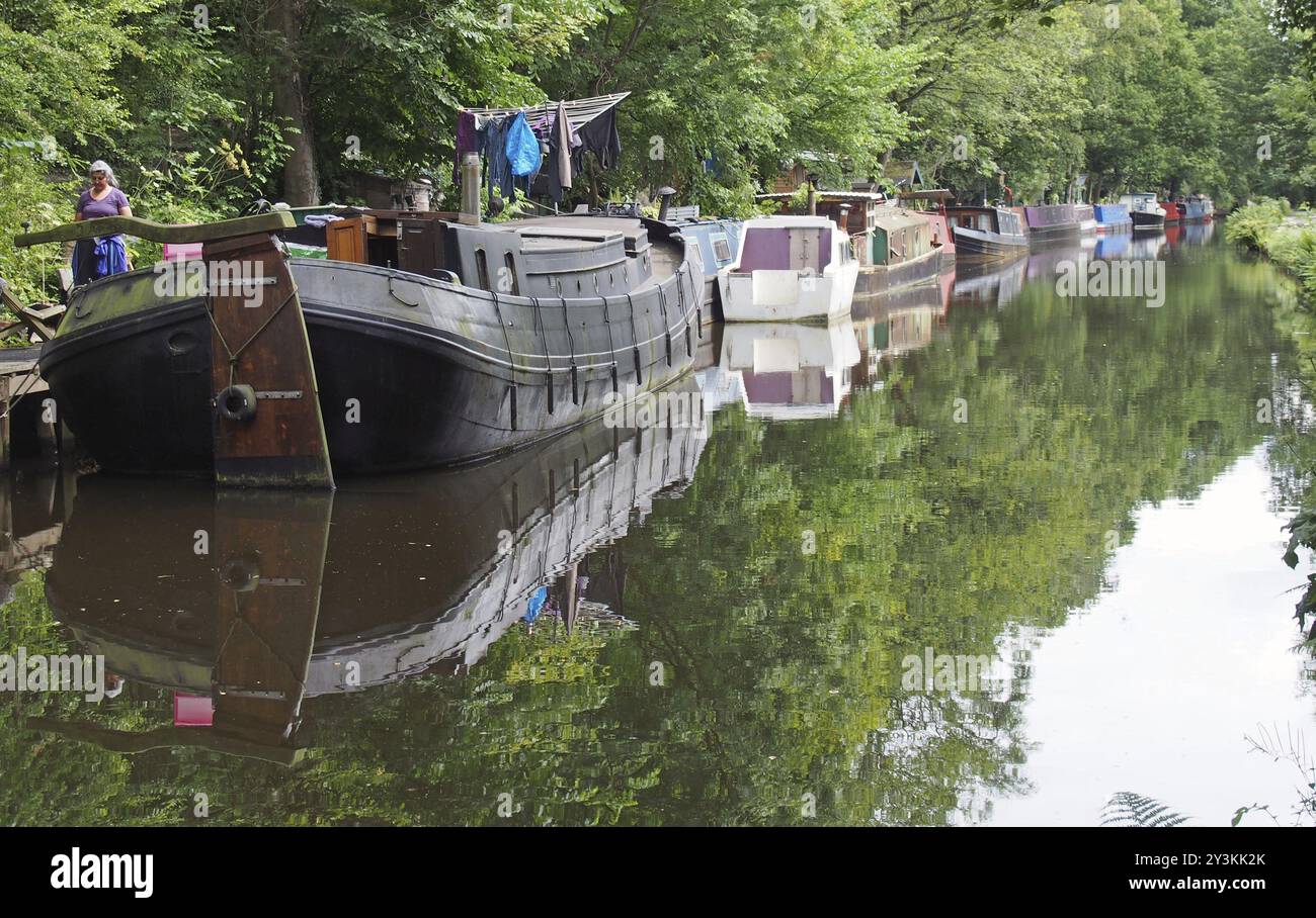 Hebden Bridge, West yorkshire, vereinigtes Königreich, 12. juli 2019: Eine Frau neben schmalen Booten und Lastkähnen vertäut am rochdale-Kanal in hebden Bridge sur Stockfoto