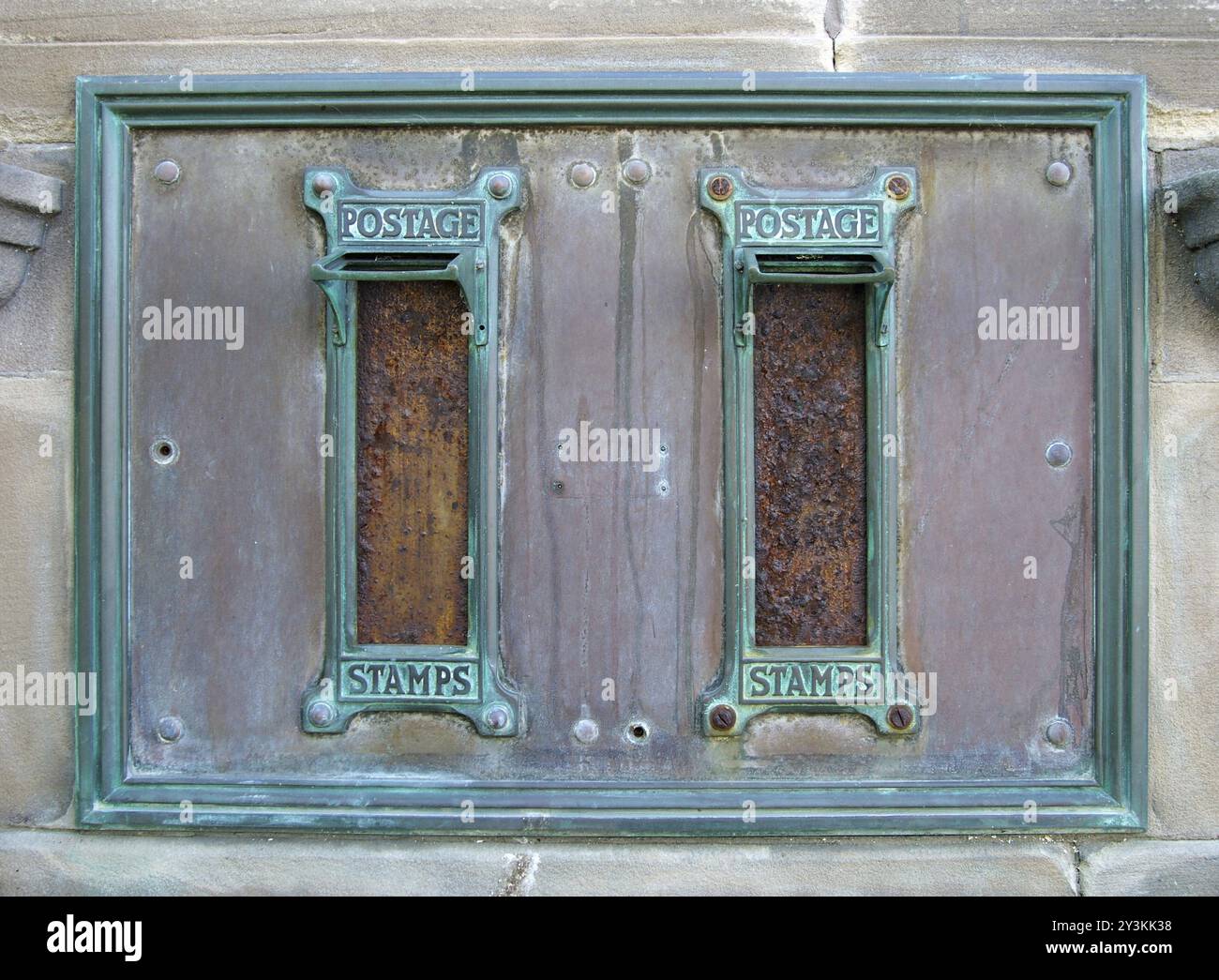 Alte britische Postfächer mit rostigen Briefschlitzen und verzierten grünen Kupferrahmen mit den Worten Briefmarken umgeben von einem alten gebeizten Metall Stockfoto