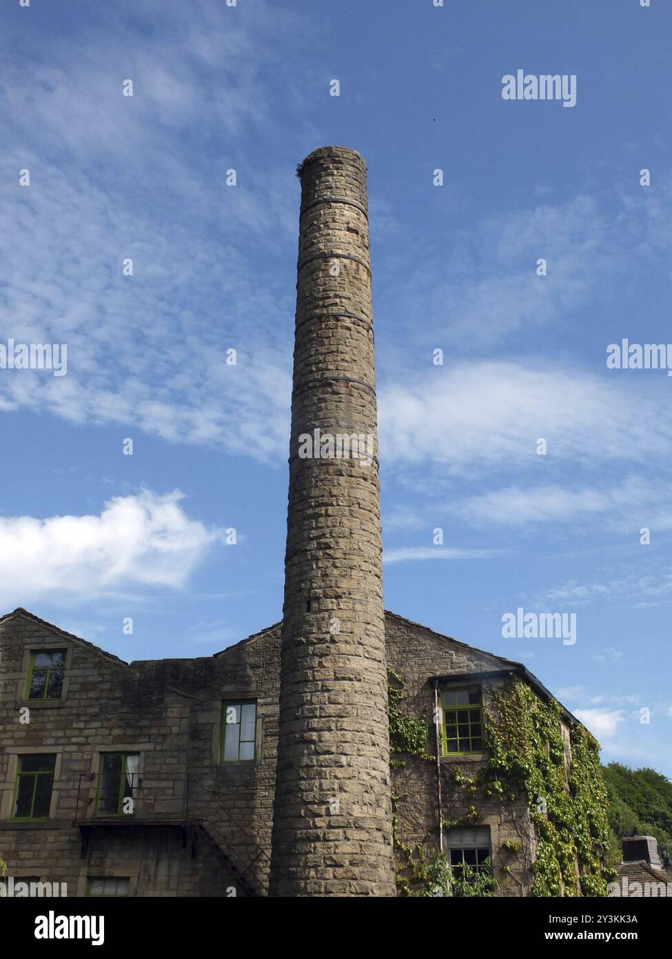 Ein altes Mühlengebäude und hoher Kamin mit blauem, bewölktem Himmel in hebden Bridge West yorkshire Stockfoto