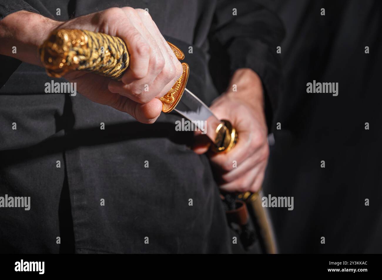 Der Samurai mit einem japanischen Katana-Schwert. Foto eines Kriegers in schwarzer Kleidung in schwachem Tastenfeld mit selektivem Fokus Stockfoto