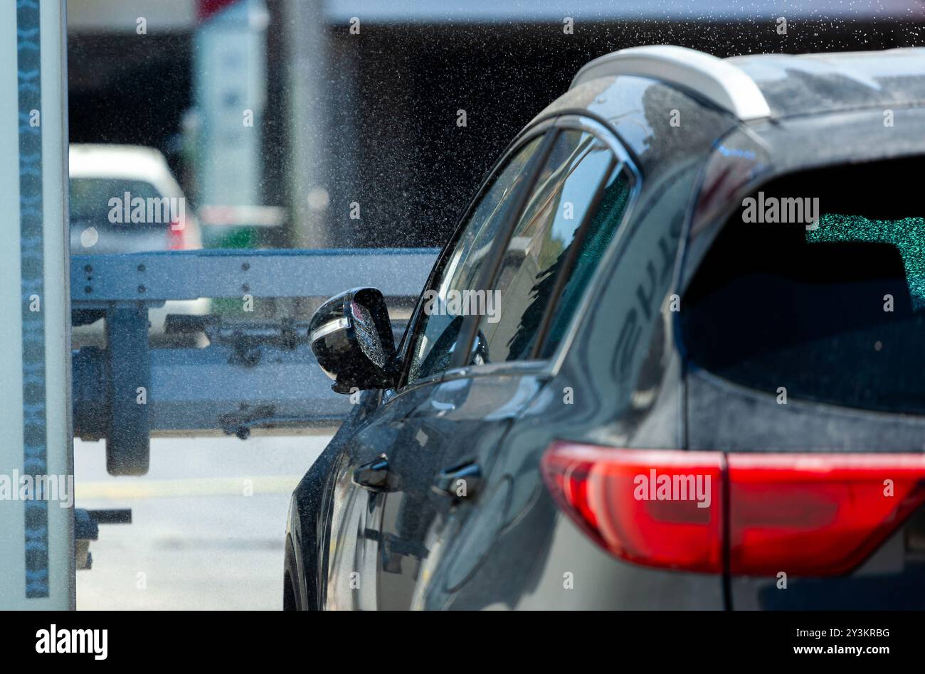 Moderne Autos werden an einem hellen Sommertag von einer automatischen Waschanlage gewaschen Stockfoto