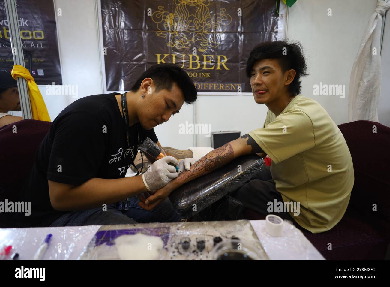 Lalitpur, Nepal. September 2024. Ein Künstler (L) färbt ein Tattoo auf den Körper eines Enthusiasten (R) während der Himalaya Tattoo Convention in Lalitpur, Nepal, am 14. August 2024. Der von der National Academy of Fine Arts und der Nepal Handicraft Association unterstützte Tattoo Summit zeigt mehr als vier Dutzend Künstler, die Götterbilder mit modernen Konzepten einfärben. (Foto: Subaas Shrestha/NurPhoto) Credit: NurPhoto SRL/Alamy Live News Stockfoto