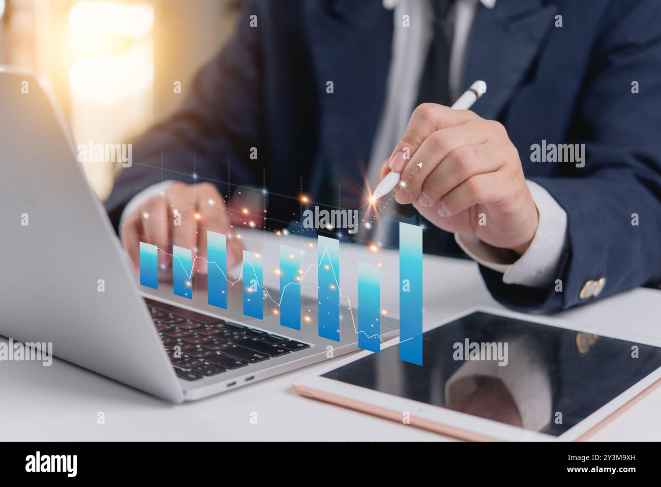 Geschäftsmann analysiert Daten mit Laptop und digitalem Tablet, berührend interaktive Grafik. Professionelles Setup für Finanzanalysen und Unternehmensplanung. Stockfoto