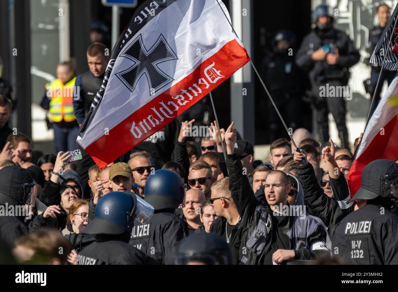 Wismar, Deutschland. September 2024. Teilnehmer einer Gegendemonstration aus dem rechten Lager werden während der Christopher Street Day (CSD) Parade von Polizisten begleitet. Nach Angaben der Polizei marschierten rund 700 bis 1000 bunt gekleidete CSD-Teilnehmer durch die Altstadt. Quelle: -/dpa/Alamy Live News Stockfoto