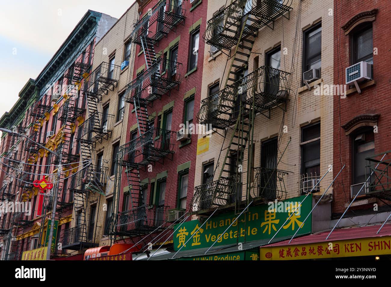 New York, USA – 14. September 2024: Blick auf die Straße mit Feuerflüchten und zweisprachigen Schildern in der lebhaften New York Chinatown, die CUL zeigt Stockfoto