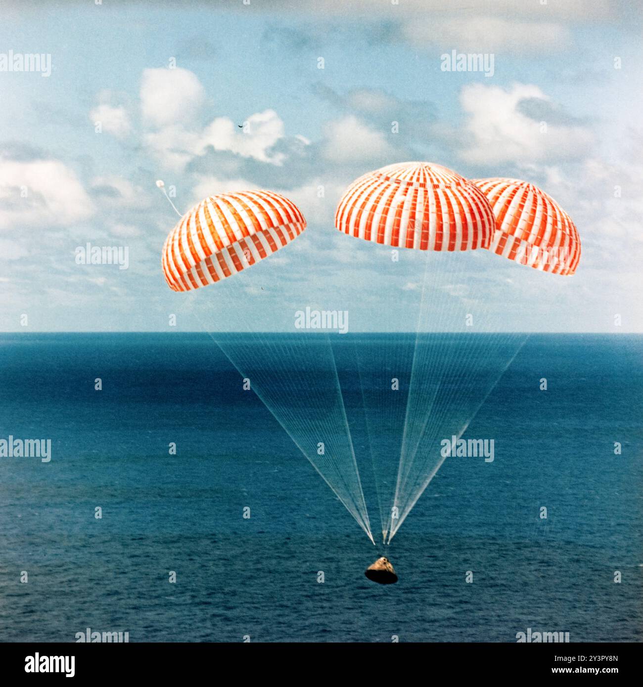 Apollo 11 Splashdown, 24. Juli 1969. Das Kommandomodul der NASA-Mission Apollo 11 fällt unter drei orange-weißen Fallschirmen sanft in Richtung Pazifik ab. Dieser legendäre Moment markierte die erfolgreiche Rückkehr der ersten Menschen auf dem Mond, der Astronauten Neil Armstrong, Buzz Aldrin und Michael Collins. Stockfoto