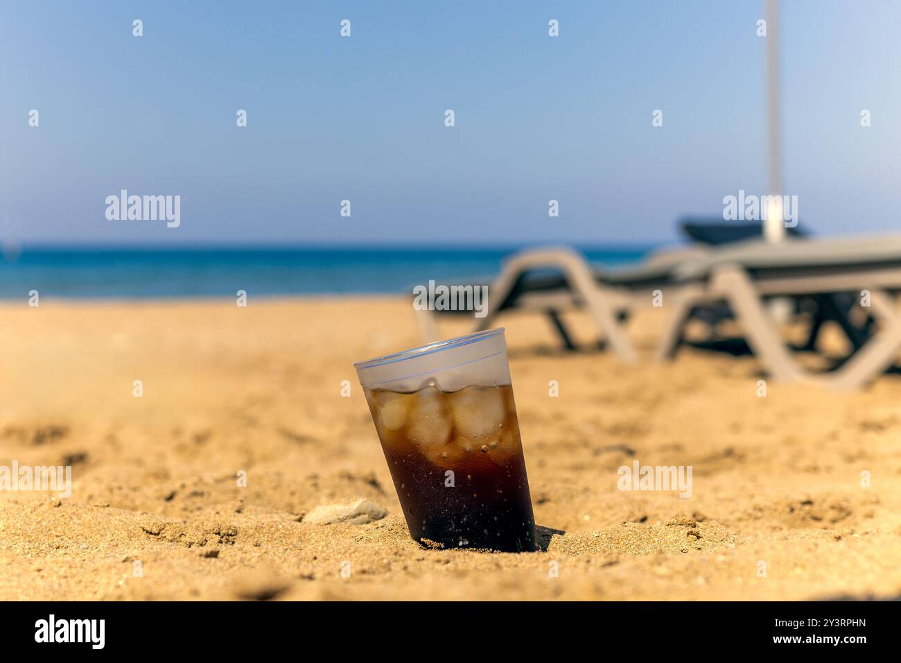 cola mit Eis am Sandstrand, kühlendem Getränk und sonnigem Tag, Urlaub und Entspannung Stockfoto