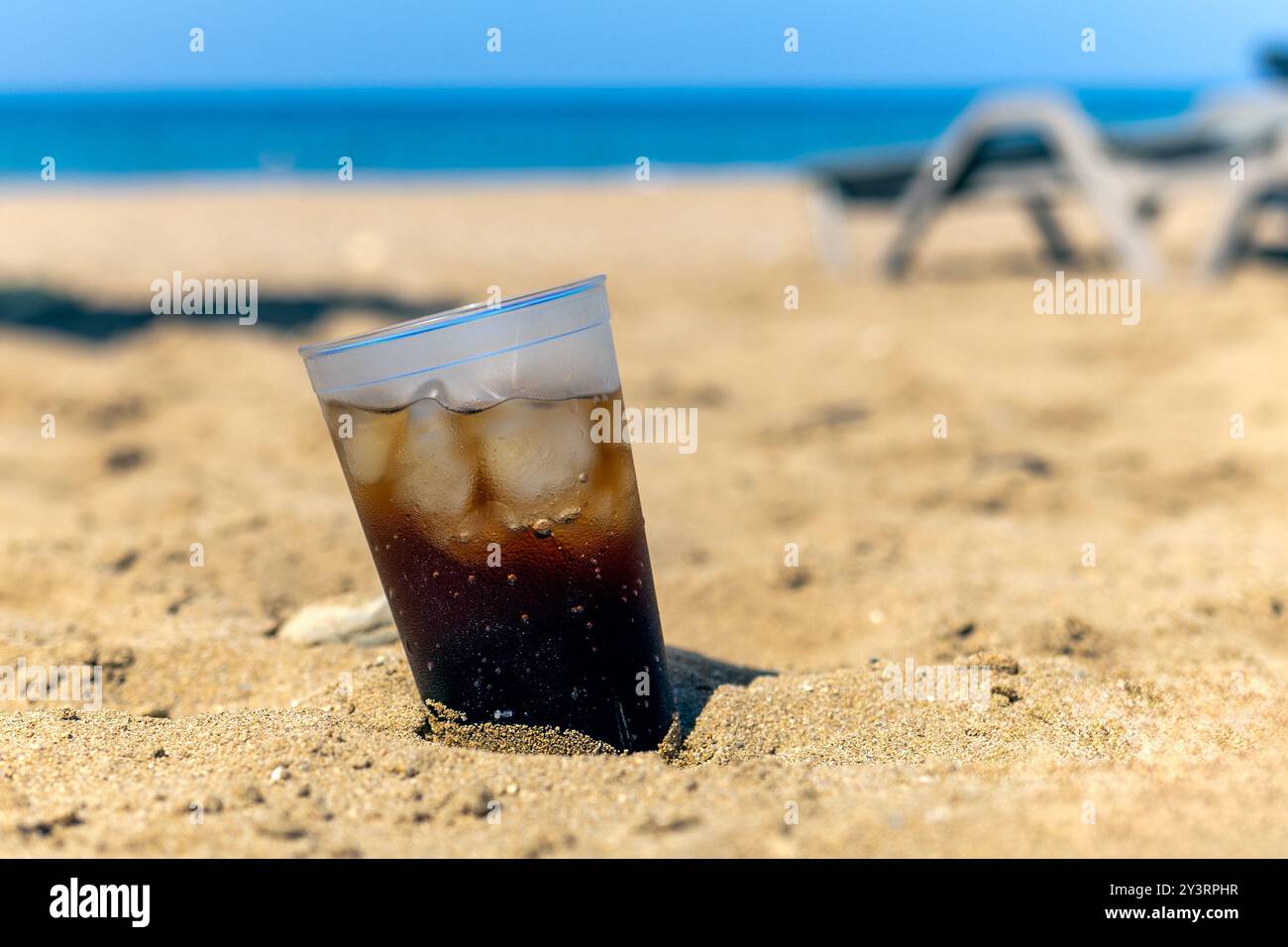 cola mit Eis am Sandstrand, kühlendem Getränk und sonnigem Tag, Urlaub und Entspannung Stockfoto