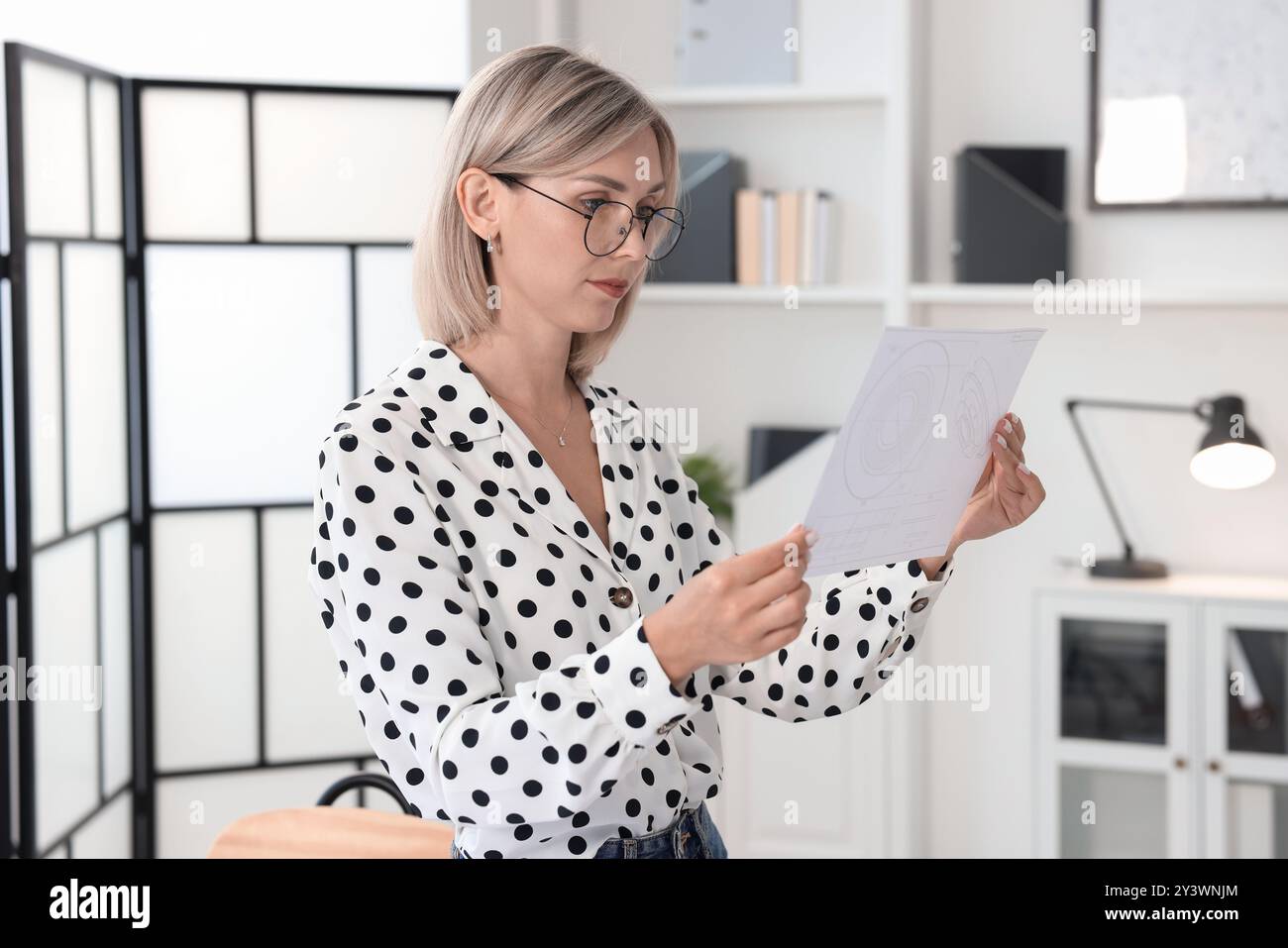 Architekt hält Papierbogen mit Konstruktionszeichnung im Büro Stockfoto