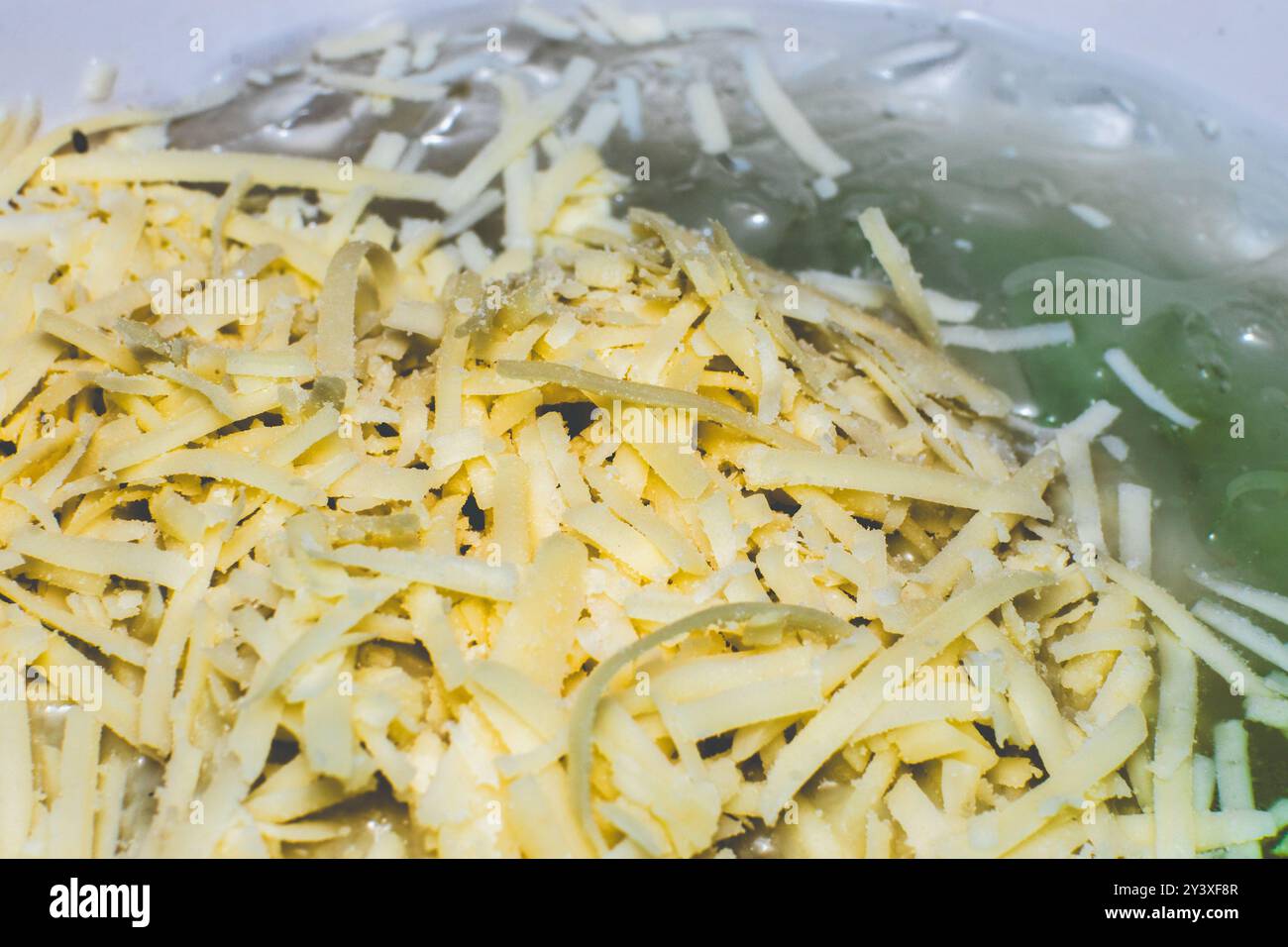 Makrofoto von geriebenem Käse mit hoher Detailgenauigkeit. Geriebener Käse als Belag auf Geschirr Stockfoto