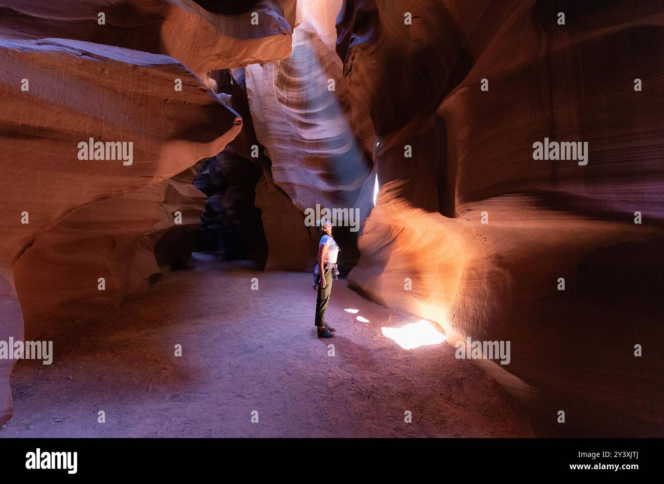 Weibliche Wanderer im farbenfrohen Slot Canyon mit Blick auf den Lichtstrahl. National Monument, Utah Stockfoto