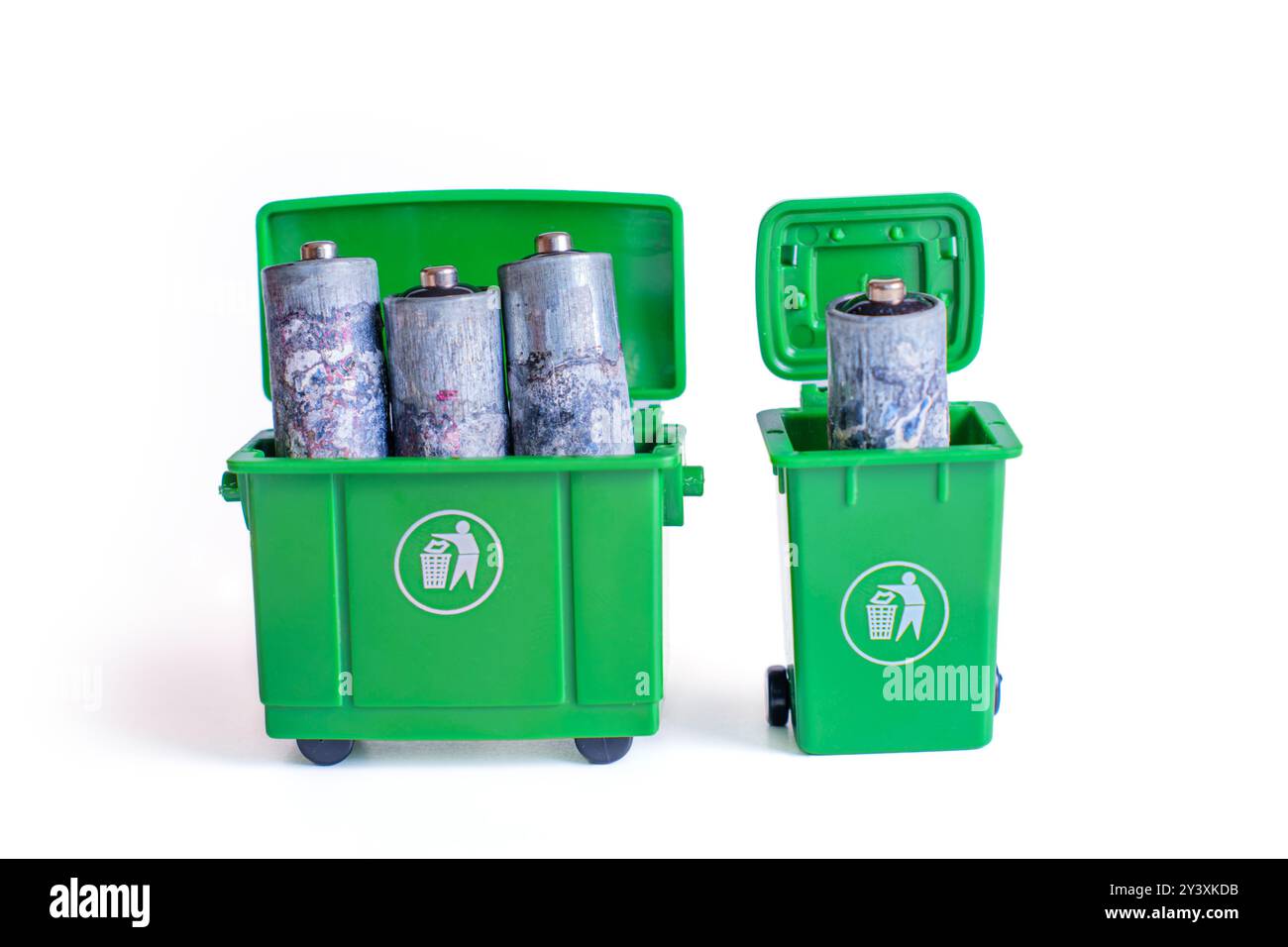 Oxidierte Batterien werden in grünen Miniaturmüllbehältern entsorgt, wodurch Recycling- und Abfallbewirtschaftungskonzepte hervorgehoben werden. Stockfoto