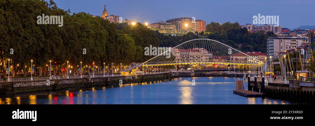 Ein breites 3:1-Panoramablick der spanischen Stadt Bilbao im Baskenland mit Blick auf den Fluss Nervión und die Calatrava-Brücke während der Dämmerung Stockfoto