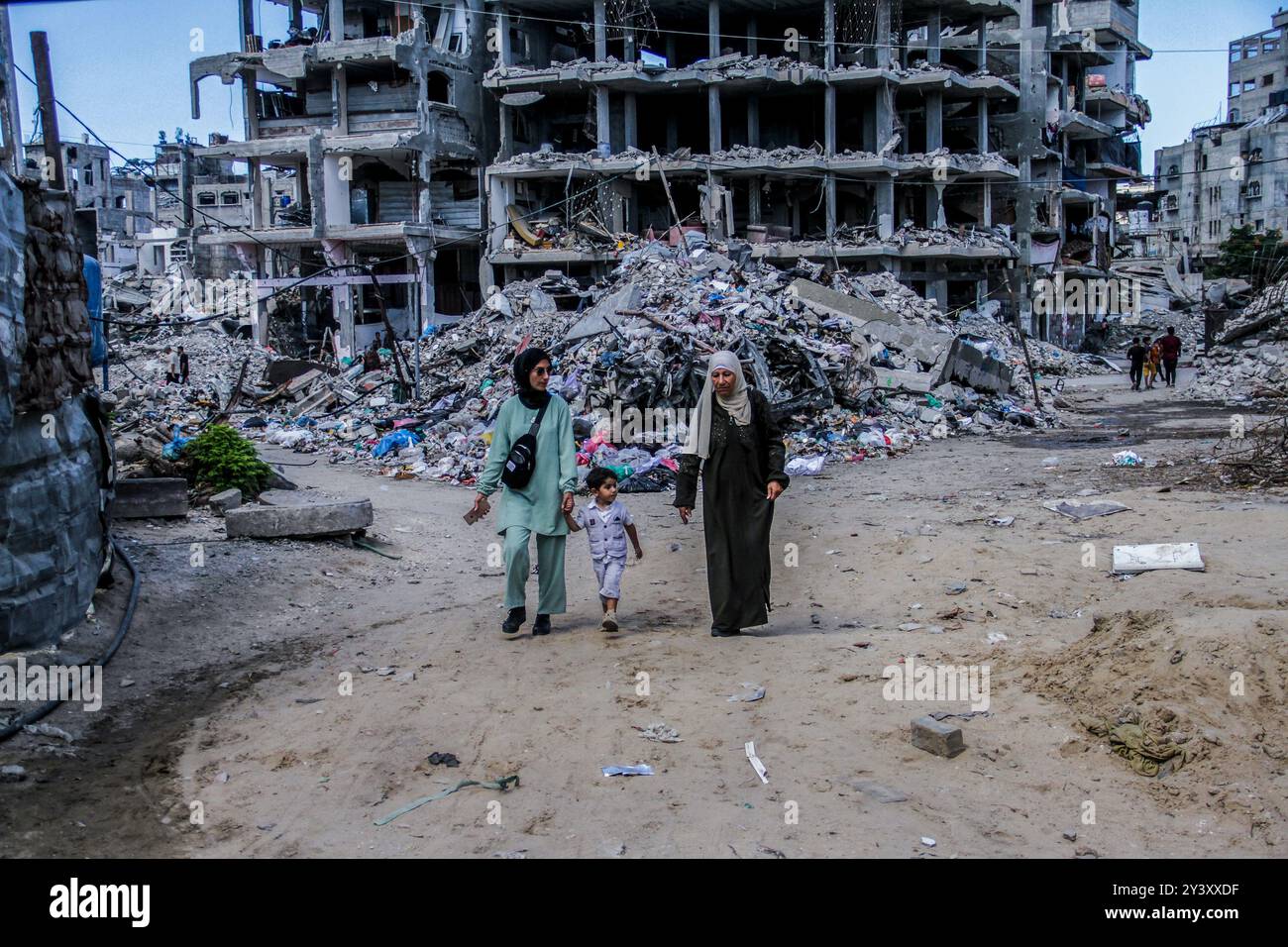 Palästinenser gehen am beschädigten Al-Aliya Kindergarten vorbei, nachdem er von einem israelischen Flugzeug im Lager Jabalia nördlich von Gaza bombardiert wurde. Der Gaza-Konflikt, der im Oktober 2023 wieder ausgebrochen war, begann mit einem überraschenden Angriff der Hamas auf israelische Städte, der zu Massensursachen und zur Entführung von Zivilisten führte. Als Reaktion darauf startete Israel schwere Luftangriffe und eine Bodenoffensive in Gaza. Die Kämpfe haben auf beiden Seiten Tausende von Toten gefordert, wobei Gaza aufgrund blockierter Hilfe und Infrastrukturschäden mit schweren humanitären Krisen konfrontiert ist. Der Konflikt hat die internationale Aufmerksamkeit mit Aufrufen zu Waffenstillstand auf sich gezogen Stockfoto