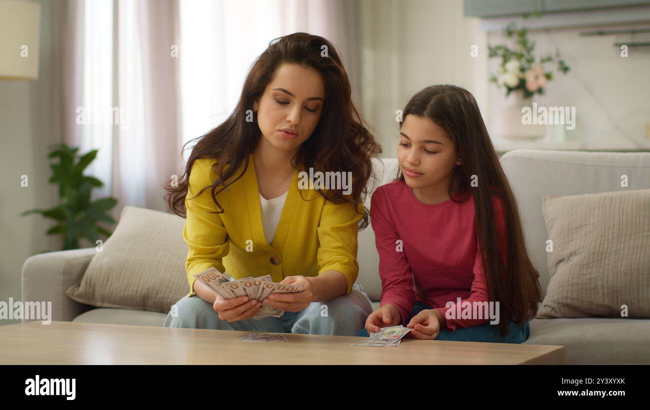 Glückliche Familie liebende Kaukasierin Mutter weibliche Mutter, die Dollar-Bargeld-Rechnung zählt und dem kleinen Mädchen Kind Kind Tochter-Taschengeld-Tasche gibt Stockfoto