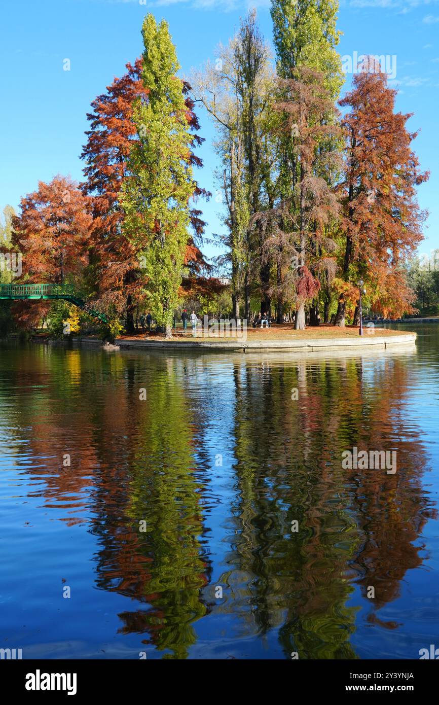 Wunderschöne Herbstlandschaft mit bunten Bäumen, See und blauem Himmel im IOR Park im Viertel Titan in Bukarest, Rumänien Stockfoto