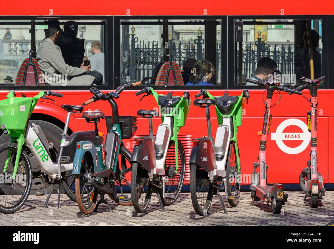 London, Großbritannien. Kalkverleih-Fahrräder parken, während ein roter Londoner Bus vorbeifährt Stockfoto