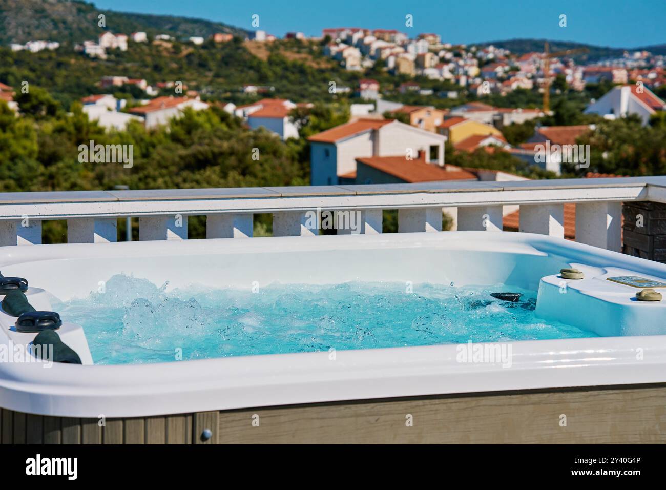 Whirlpool im Freien auf der sonnigen Dachterrasse mit sprudelndem Wasser und komfortablen Sitzgelegenheiten mit wunderschönem Blick auf die touristische Stadtlandschaft. Ort zum Entspannen und Stockfoto