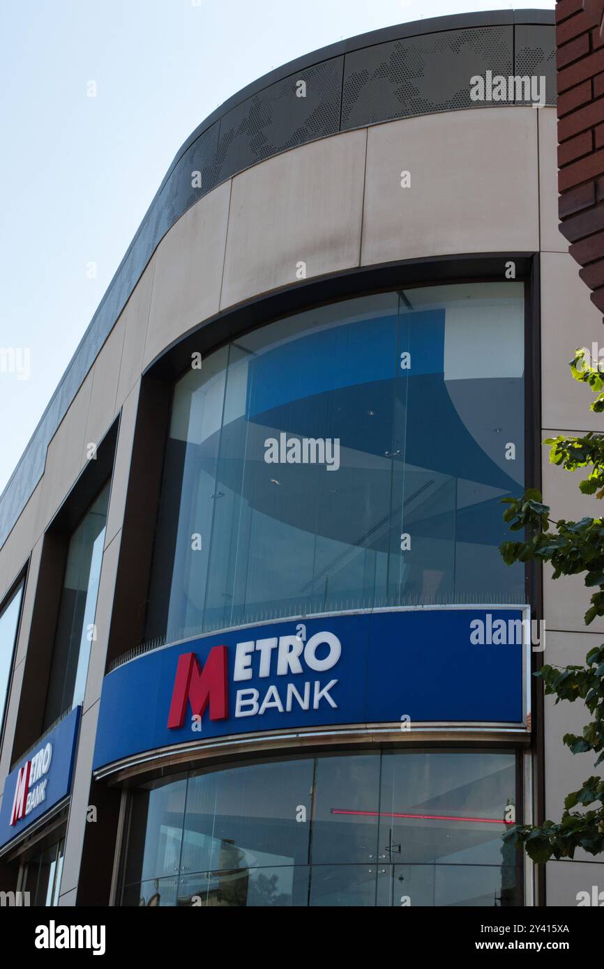 Ein modernes Bankgebäude mit großen Glasfenstern und einem auffälligen blau-roten Schild mit dem Namen „Metro Bank“. Die Architektur verfügt über einen geschwungenen Stockfoto