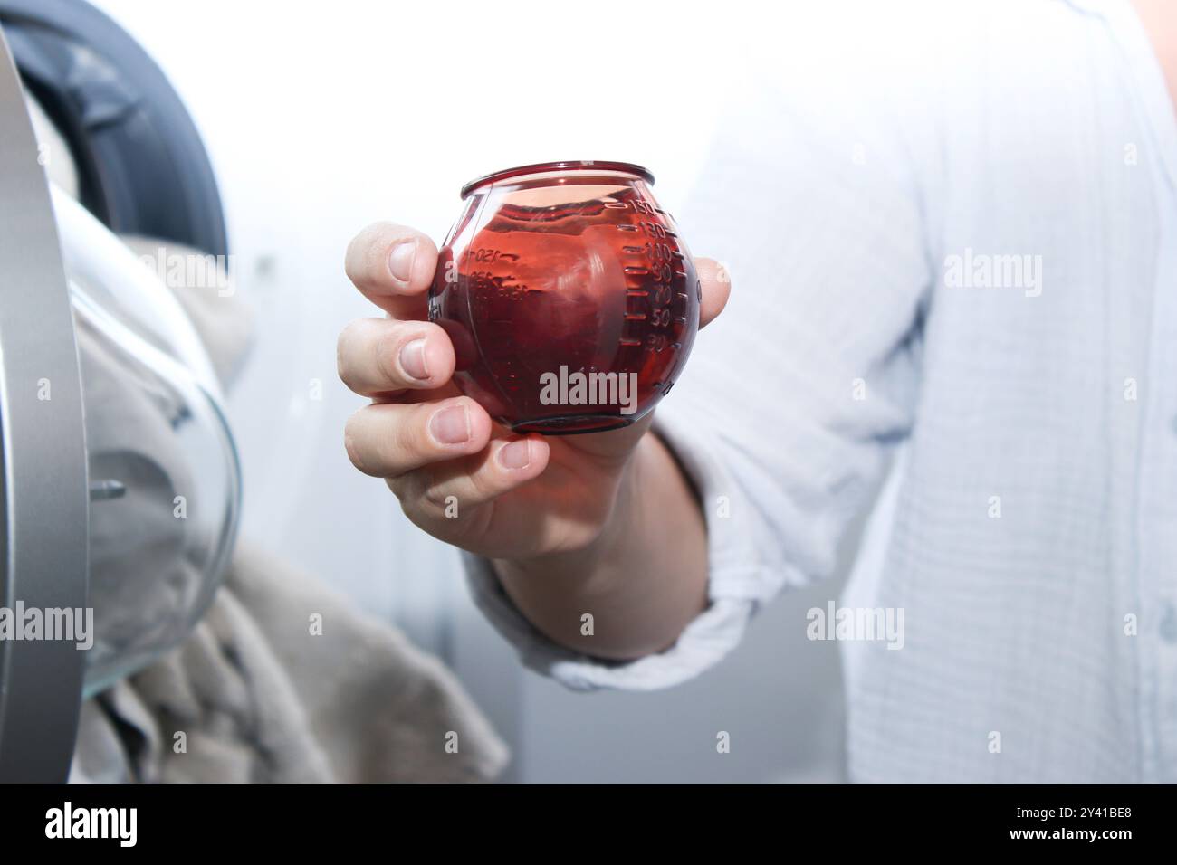 Nahaufnahme einer Frau, die einen Becher mit Waschmittel hält Stockfoto