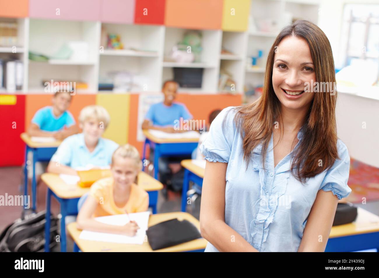Frau, Lächeln und Porträt der Lehrerin im Klassenzimmer mit Schülern zum Lernen, Wissen und Entwicklung. Weibliche Person, glücklich und zuversichtlich Stockfoto