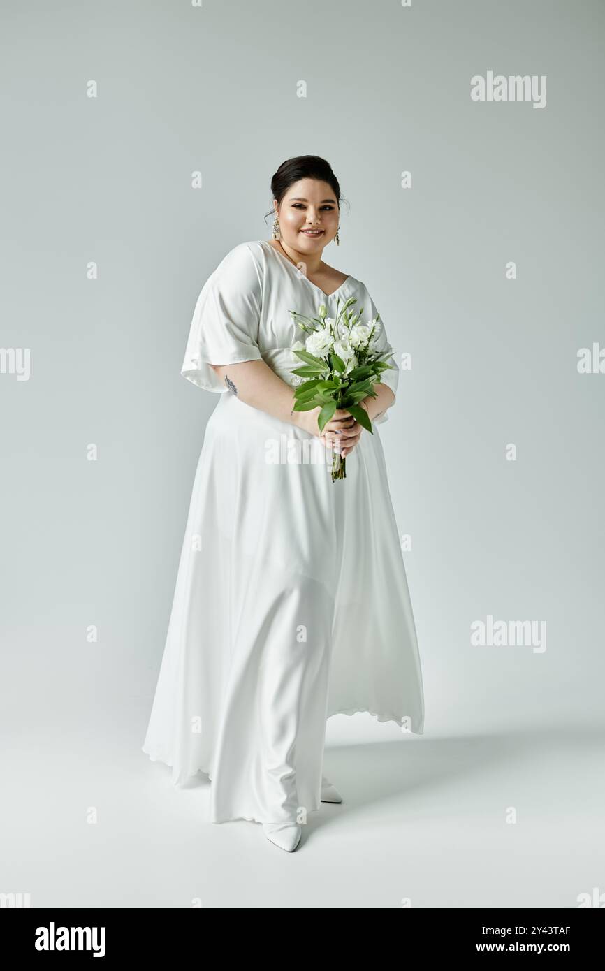 Eine atemberaubende Braut strahlt Vertrauen in ein fließendes weißes Kleid aus, während sie einen wunderschönen Blumenstrauß hält. Stockfoto