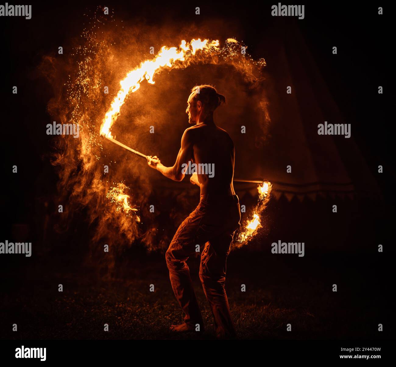 Eine bezaubernde Feuertänzerin zeigt ihr Talent während einer Vorstellung mit faszinierenden Flammen Stockfoto