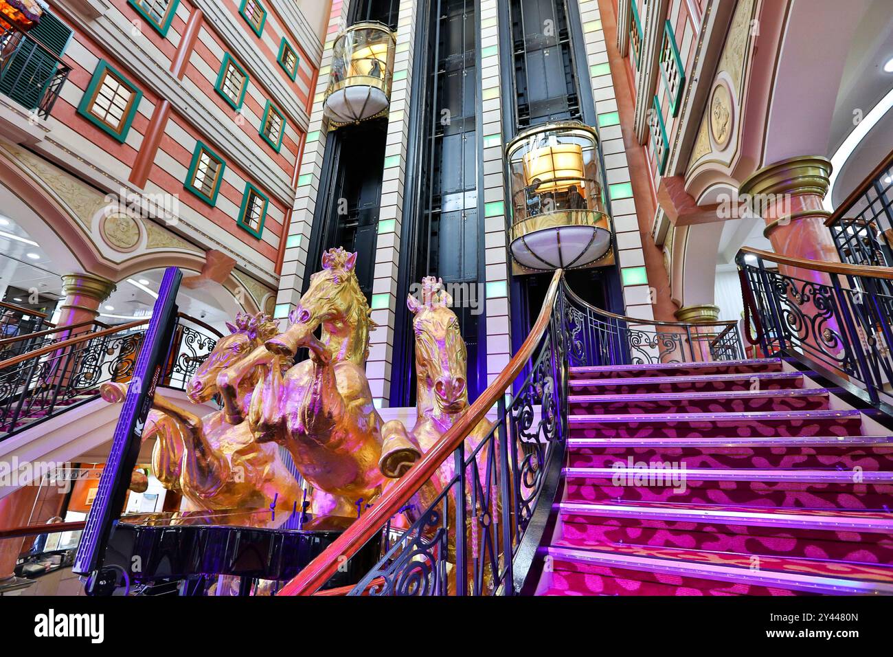 Asiatisches Kreuzfahrtschiff farbenfrohes Atrium, Treppen, Lobby, Innenraum, goldene Pferde, die eine Statue aufziehen, Panoramablick-Glasaufzüge, Star Cruises Superstar Virgo Stockfoto