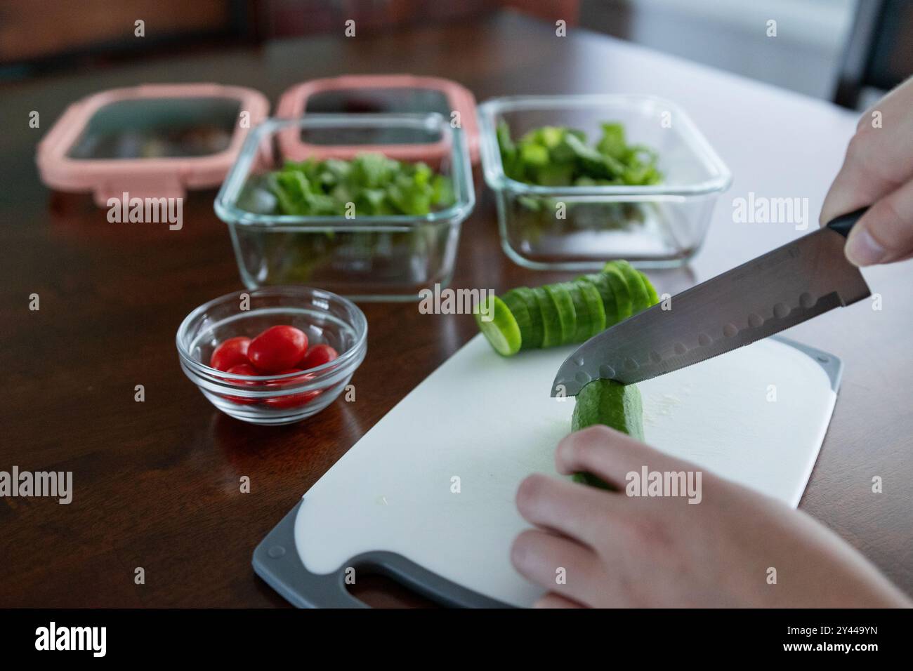 Person, die Gurken für die Zubereitung von Mahlzeiten schneidet Stockfoto