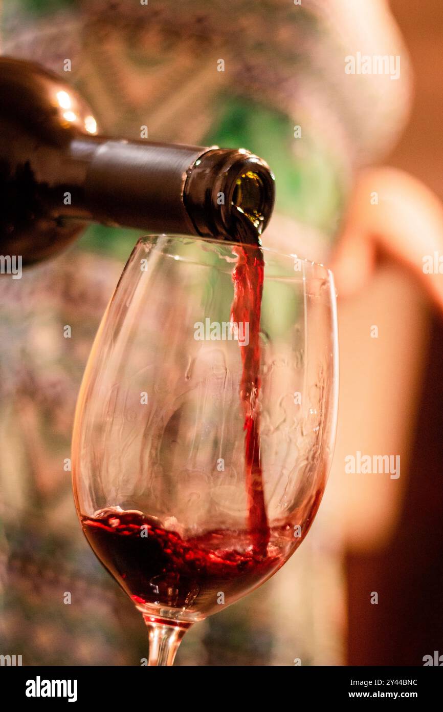 Ein Glas Rotwein wird aus einer Flasche gegossen Stockfoto