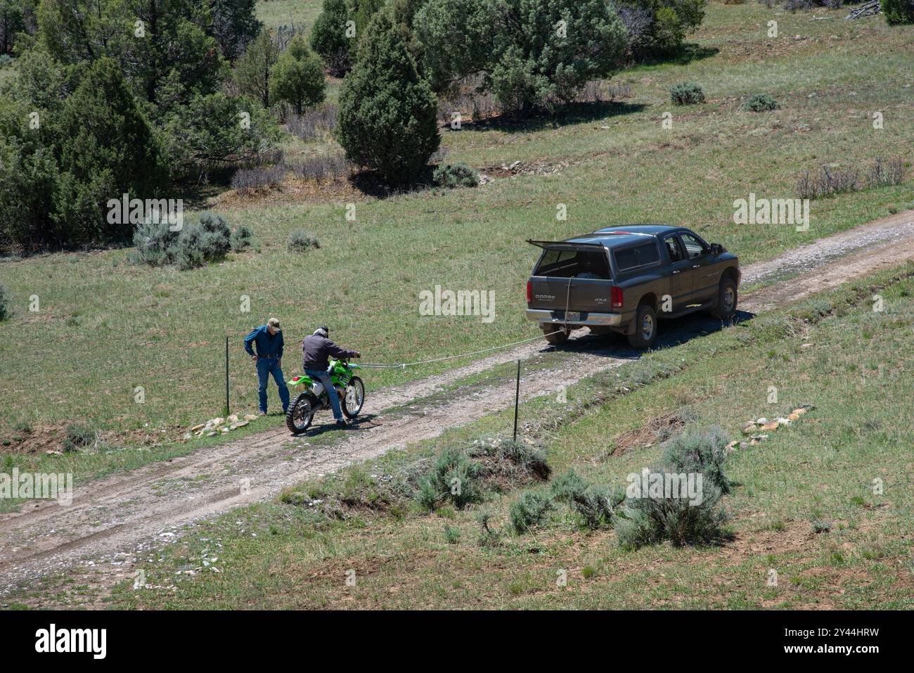 Zwei Männer schleppen ein grünes Motorrad, das nicht hinter einem Pickup-Truck anfängt, um zu reden, im Norden von New Mexico, USA. Stockfoto