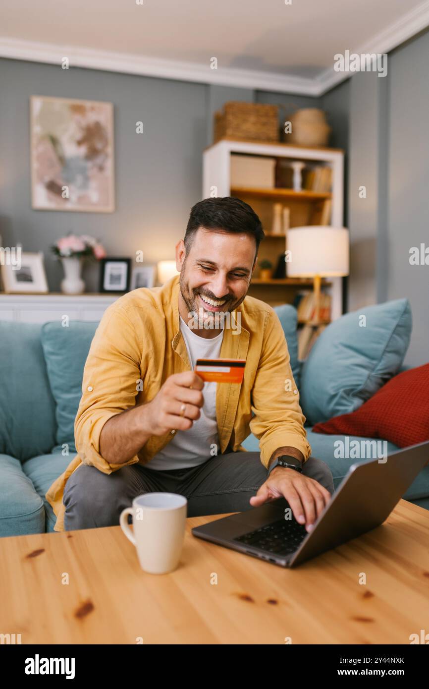 Lächelnder Mann, der Kartendetails für eine Online-Transaktion eingibt Stockfoto