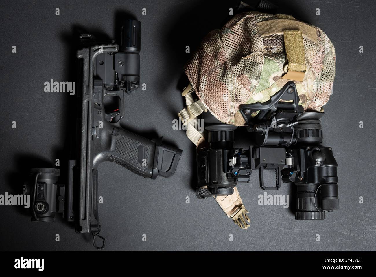Taktische Ausrüstung und Waffen, Kappe und binokulares Nachtsichtgerät, Pistole mit Hinterschaft, Rotpunktvisier und Taschenlampe. Stockfoto