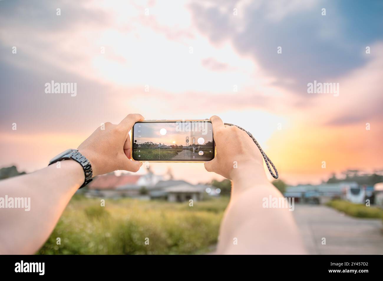 Ein Mann, der Fotos von der Landschaft macht. Er benutzt eine Handykamera. Am Nachmittag in einer hellen natürlichen Atmosphäre. Stockfoto