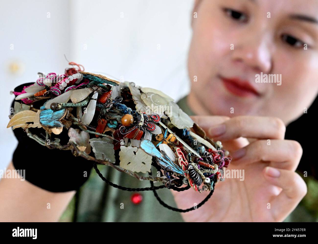 (240916) -- LUOYANG, 16. September 2024 (Xinhua) -- Chu Mengdan beobachtet ein handwerkliches Perlenweben in einer Erlebnishalle für immaterielles Kulturerbe in der Stadt Luoyang, Zentralchinas Provinz Henan, 12. September 2024. Chu Mengdan ist der Erben der vierten Generation von Bead Weaving Skills, einem Projekt des immateriellen Kulturerbes im Bezirk Chanhe in Luoyang. Die Kunst, Perlen so klein wie Reiskörner zu nähten und zu einzigartigen Mustern oder Formen zu verbinden, wird als Perlenweben bezeichnet, das in Kleidung und Schmuck verwendet wird. Der Herstellungsprozess der exquisiten Handwerkskunst mit Perlen ist viel komplizierter als Stockfoto