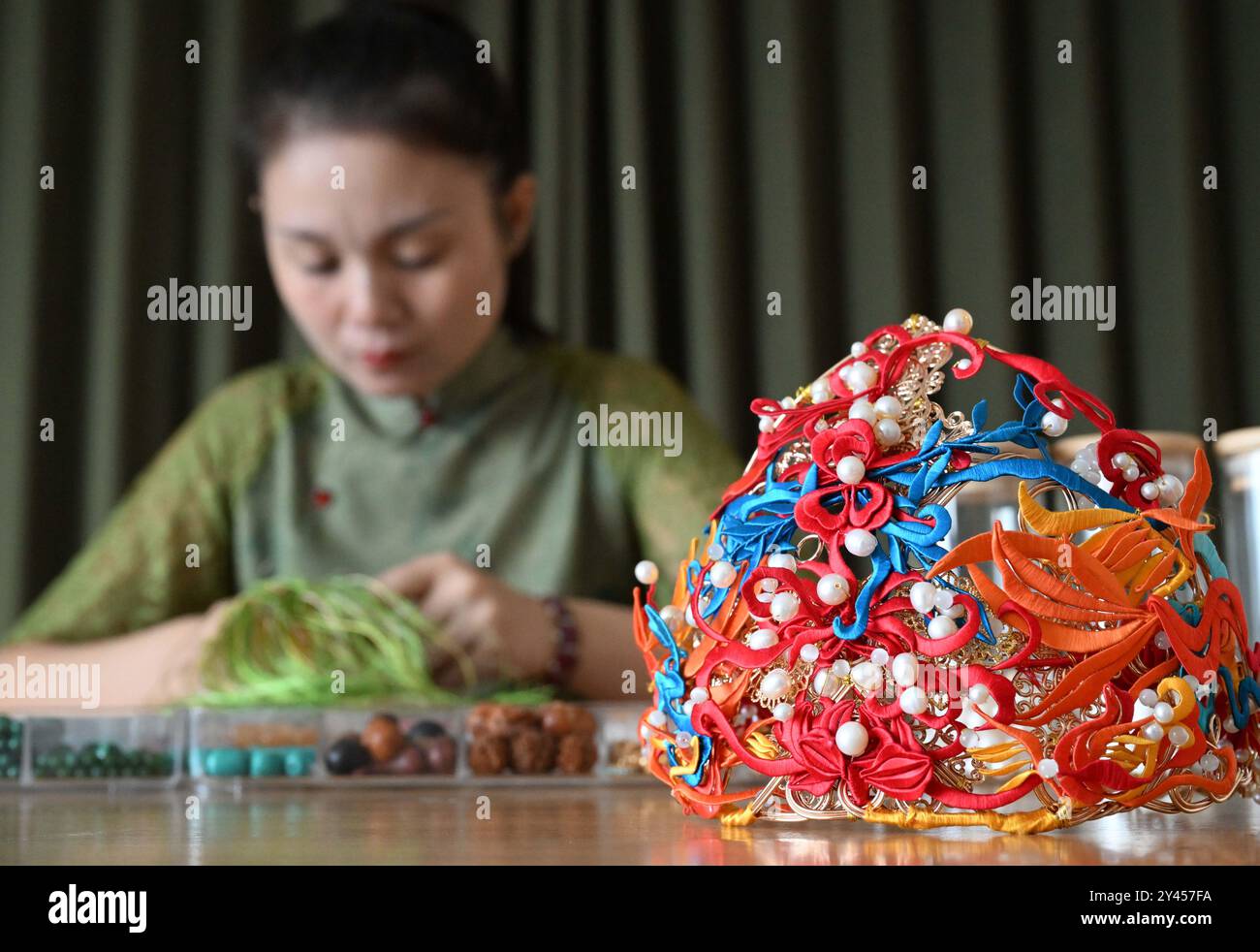 (240916) -- LUOYANG, 16. September 2024 (Xinhua) -- Chu Mengdan fertigt Kunsthandwerk für Perlenweben in einer Erlebnishalle des immateriellen Kulturerbes in der Stadt Luoyang, Zentralchinas Provinz Henan, 12. September 2024. Chu Mengdan ist der Erben der vierten Generation von Bead Weaving Skills, einem Projekt des immateriellen Kulturerbes im Bezirk Chanhe in Luoyang. Die Kunst, Perlen so klein wie Reiskörner zu nähten und zu einzigartigen Mustern oder Formen zu verbinden, wird als Perlenweben bezeichnet, das in Kleidung und Schmuck verwendet wird. Der Herstellungsprozess der exquisiten Handwerkskunst mit Perlen ist viel komplizierter als er ist Stockfoto