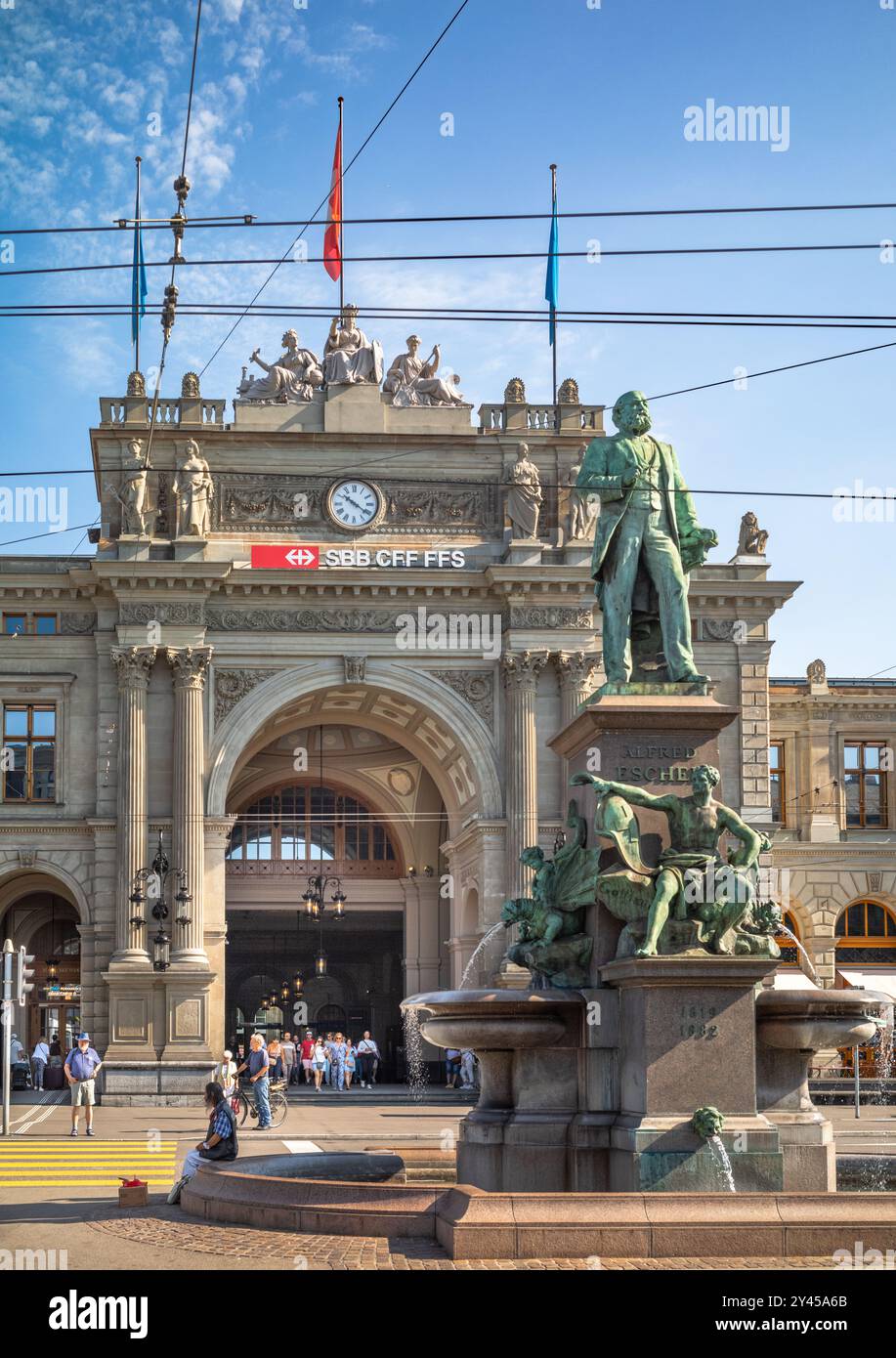 Die Statue von Alfred Escher, dem Eisenbahnkönig, vor der Neorenaissance-Fassade von Zürich HB, einem der berühmtesten Bahnhöfe der Schweiz. Stockfoto