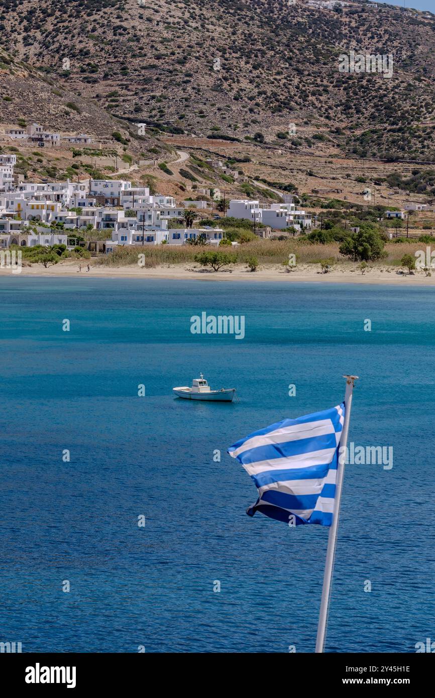 Blick auf die griechische Nationalflagge, ein Fischerboot und das blaue Meer in Sifnos Griechenland Stockfoto